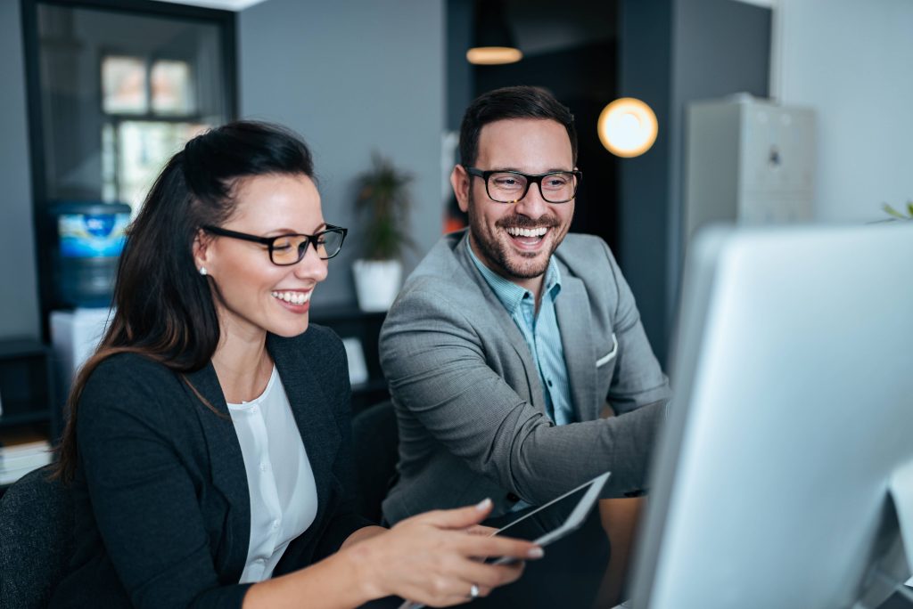 En ung kvinde og mand, der sidder ved en computer og snakker